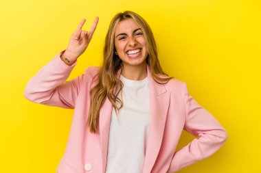 Sarı arka planda izole edilmiş genç sarışın kadın parmaklarıyla taş hareketi gösteriyor.