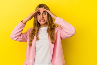 Sarışın, beyaz bir kadın sarı arka planda izole edilmiş. Hoş bir sürprizle karşılaşıyor, heyecanlı ve el kaldırıyor..