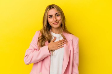 Sarı arka planda izole edilmiş genç sarışın kadın yemin ediyor, elini göğsüne koyuyor..