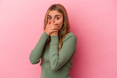 Pembe arka planda izole edilmiş, elleri endişeli görünen genç sarışın beyaz kadın..