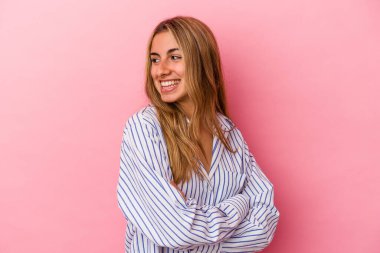 Genç sarışın beyaz kadın pembe arka planda izole edilmiş gülüyor ve eğleniyor..