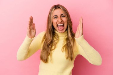 Pembe arka planda izole edilmiş genç sarışın kadın hoş bir sürpriz yaşıyor, heyecanlı ve el kaldırıyor..