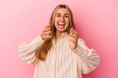 Pembe arka planda izole edilmiş genç sarışın kadın kameraya sarıldığı için kendinden emin hissediyor..