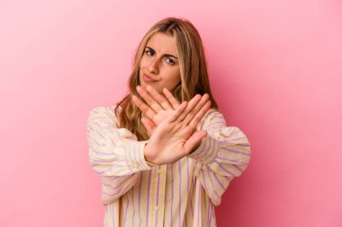 Pembe arka planda izole edilmiş genç sarışın kadın inkar jesti yapıyor.