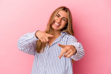 Pembe arka planda izole edilmiş genç, sarışın, beyaz bir kadın..