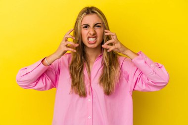Sarı arka planda izole edilmiş genç sarışın kadın gergin elleriyle çığlık atıyor..