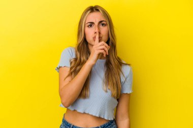Sarışın, beyaz bir kadın. Sarı arka planda izole edilmiş. Sır saklıyor ya da sessizlik istiyor..