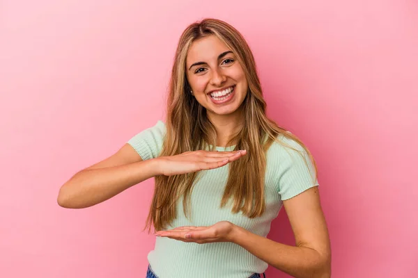 Jovem Loira Caucasiana Isolada Fundo Rosa Segurando Algo Com Ambas — Fotografia de Stock