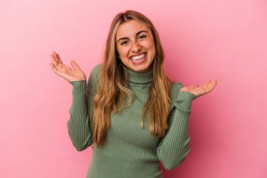 Pembe arka planda soyutlanmış genç sarışın beyaz kadın kollarıyla ölçeği yapıyor, mutlu ve kendinden emin hissediyor..