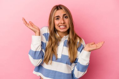 Pembe arka planda soyutlanmış, kafası karışmış ve omuz silkmiş genç, sarışın bir kadın..