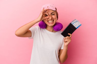 Elinde pasaport ve seyahat biletleri olan beyaz saçlı genç bir kadın pembe arka planda tek başına heyecanlı..