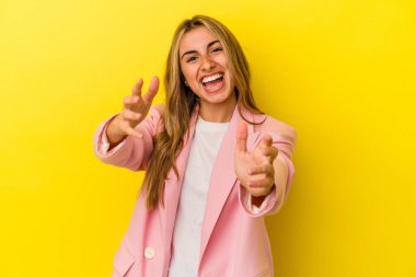 Sarı arka planda izole edilmiş genç sarışın beyaz kadın kameraya sarıldığı için kendinden emin..