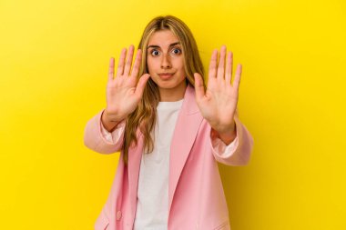 Sarışın, beyaz, sarı arka planda izole edilmiş genç bir kadın yakın bir tehlike nedeniyle şoka uğruyor.