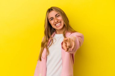 Sarışın, beyaz bir kadın, sarı arka planda izole edilmiş, parmaklarıyla ön tarafı işaret ediyor..