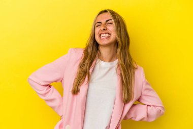 Sarışın, beyaz bir kadın. Sarı arka planda izole edilmiş. Rahatlamış ve mutlu bir şekilde gülüyor..