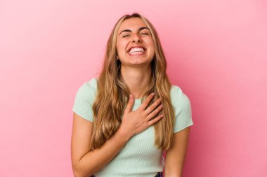 Pembe arka planda soyutlanmış genç sarışın beyaz kadın kahkahalarla gülüyor..