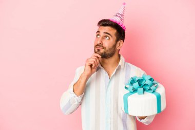 Pembe arka planda mahsur kalmış, şüpheli ve şüpheci bir ifadeyle yan bakan beyaz bir adam doğum gününü kutluyor..