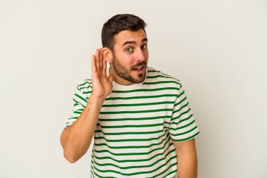 Beyaz arka planda izole edilmiş genç beyaz adam bir dedikoduyu dinlemeye çalışıyor..