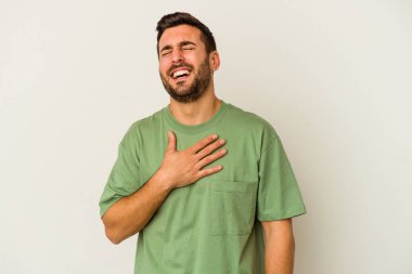 Beyaz arka planda izole genç beyaz adam yüksek sesle gülüyor elini göğsüne koyuyor..