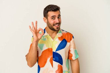 Beyaz arka planda izole edilmiş genç beyaz bir adam bir göz kırptı ve elleriyle iyi bir jest yaptı..