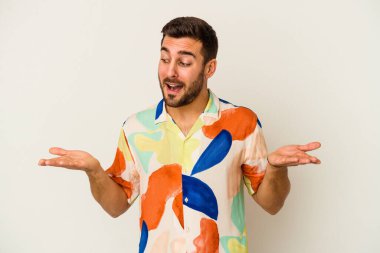 Beyaz arka planda izole edilmiş genç beyaz bir adam elinde avuç içi bir şeyle kameraya sunuyor..