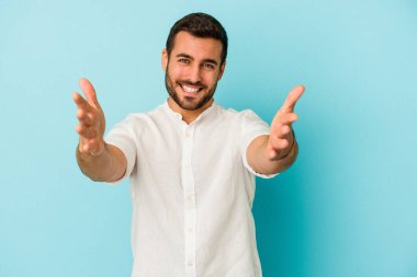 Mavi arka planda izole edilmiş genç beyaz adam kameraya sarıldığı için kendinden emin hissediyor..