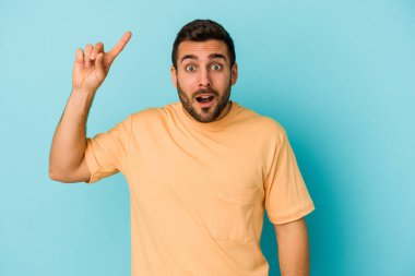 Kafkasyalı genç adam mavi arka planda izole edildi. Harika bir fikri var, yaratıcılık kavramı..