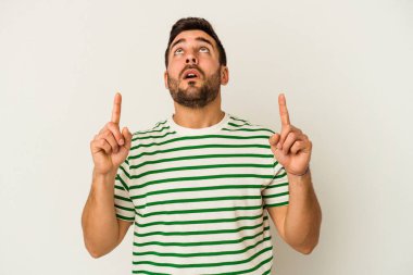 Beyaz arka planda izole edilmiş genç beyaz adam ağzı açık bir şekilde üst tarafı işaret ediyor..