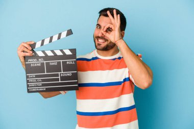 Kafkasyalı genç bir adam mavi arka planda izole edilmiş bir alçıpan tutuyor..