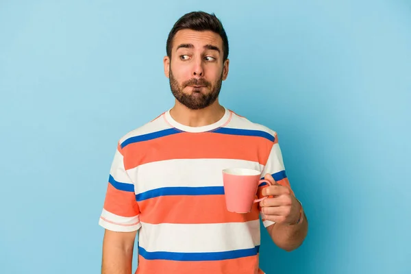 Joven Hombre Caucásico Sosteniendo Una Taza Aislada Sobre Fondo Azul — Foto de Stock