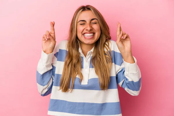 stock image Young blonde caucasian woman isolated on pink background crossing fingers for having luck
