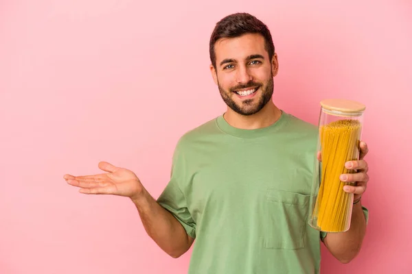 Ung Kaukasier Man Hålla Pasta Burk Isolerad Rosa Bakgrund Visar — Stockfoto