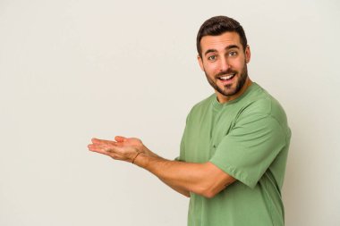 Beyaz arka planda izole edilmiş beyaz tenli genç bir adam palmiyesinde bir kopya alanı tutuyor..