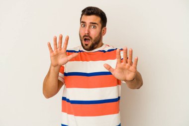 Beyaz arka planda izole genç beyaz adam yakın bir tehlike nedeniyle şoka uğruyor