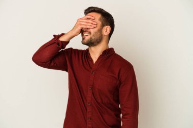 Beyaz arka planda izole olmuş genç beyaz bir adam ellerini başının üstünde tutarak neşeyle gülüyor. Mutluluk kavramı.