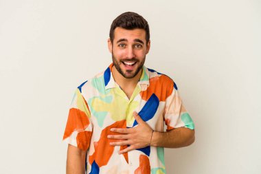 Beyaz arka planda izole genç beyaz adam yüksek sesle gülüyor elini göğsüne koyuyor..