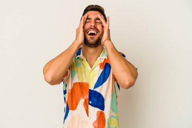 Beyaz arka planda izole olmuş genç beyaz bir adam ellerini başının üstünde tutarak neşeyle gülüyor. Mutluluk kavramı.