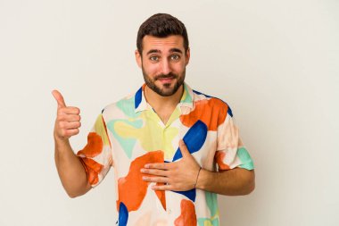 Beyaz arka planda izole edilmiş genç beyaz adam karnına dokunuyor, nazikçe gülümsüyor, yemek yiyor ve tatmin oluyor..