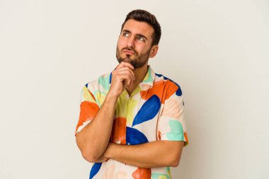 Beyaz arka planda soyutlanmış genç beyaz bir adam düşünüyor ve yukarı bakıyor, yansıtıyor, düşünüyor, hayal kuruyor..