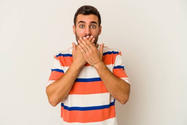 Beyaz arka planda izole edilmiş genç beyaz adam şok olmuş, ağzı ellerle kaplanmış, yeni bir şey keşfetmeye hevesli..