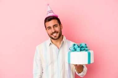 Pembe arka planda izole edilmiş, mutlu, gülümseyen ve neşeli bir şekilde doğum gününü kutlayan beyaz bir genç..
