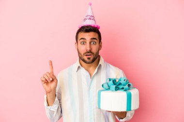 Genç beyaz adam doğum gününü pembe arka planda izole bir şekilde kutluyor. Harika bir fikri var, yaratıcılık kavramı..