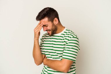 Beyaz arka planda izole edilmiş genç beyaz bir adam kameraya parmaklarıyla göz kırpıyor, yüzünü kapatmaktan utanıyor..