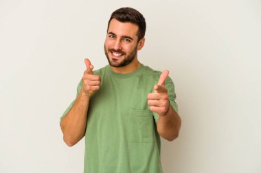 Beyaz arka planda izole edilmiş genç beyaz adam parmaklarıyla ön tarafı işaret ediyor..