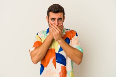 Beyaz arka planda izole edilmiş genç beyaz bir adam ağzı kapalı ve elleri endişeli görünüyor..