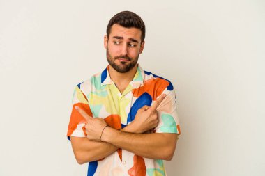 Beyaz arka plan noktalarında izole genç beyaz adam, iki seçenek arasında seçim yapmaya çalışıyor.