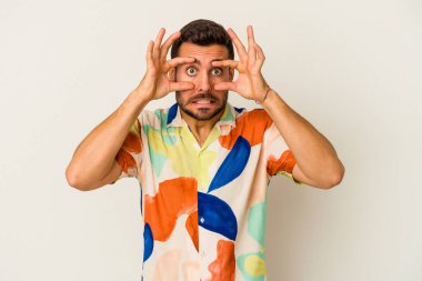 Beyaz arka planda izole edilmiş genç beyaz bir adam bir başarı fırsatı bulmak için gözlerini açık tutuyor..