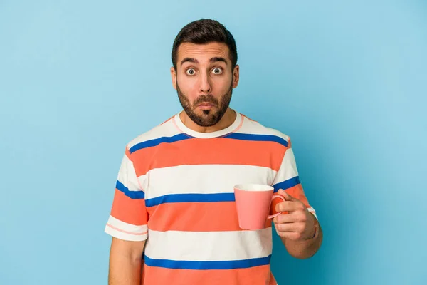 Junger Kaukasischer Mann Mit Tasse Auf Blauem Hintergrund Zuckt Mit — Stockfoto