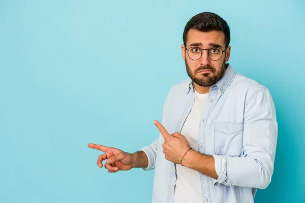 Jovem Caucasiano Isolado Fundo Azul Chocado Apontando Com Dedos Indicadores — Fotografia de Stock