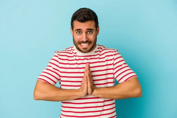 Jovem Caucasiano Isolado Fundo Azul Mãos Dadas Rezar Perto Boca — Fotografia de Stock